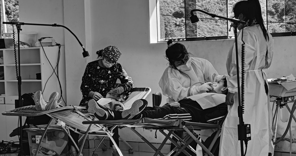People providing dental care beside portable treatment chairs